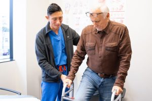 Provider Helping Man With Walker