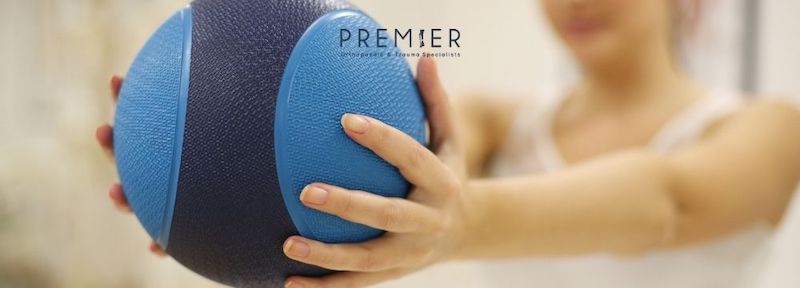 Woman at physical therapy with medicine ball regaining strength and function after an orthopedic injury and treatment at Premier Orthopaedic & Trauma Specialists